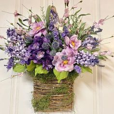 a basket filled with purple flowers sitting on top of a white door sill next to a wall