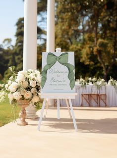 a welcome sign with flowers in front of an outdoor ceremony area at a wedding venue