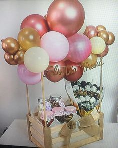 a wooden crate filled with lots of balloons and confetti on top of a table