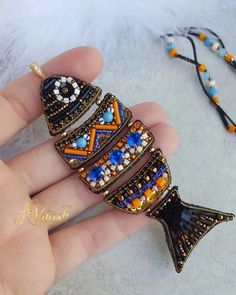 a hand is holding a colorful brooch with beads and bead work on it