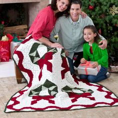 the family is posing for a photo in front of their christmas tree with presents and gifts