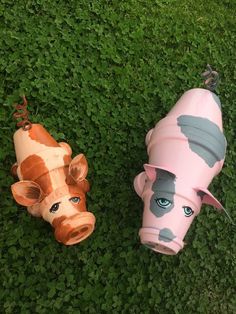 two toy cows laying in the grass with their heads turned to look like they are looking at something