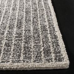 a gray and white rug on a black surface