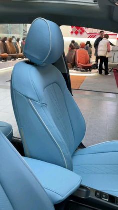 the interior of a car with blue leather seats and people in the background looking at it