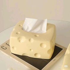 a piece of cheese sitting on top of a table next to a tissue dispenser