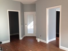 an empty room with hard wood flooring and white trim on the door, and gray walls