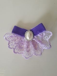 a purple and white brooch with a pearl on it's center, sitting on a table