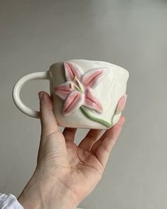 a hand holding a white coffee cup with pink flowers on it