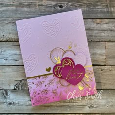 a pink and gold valentine's day card on a wooden background with heart cutouts