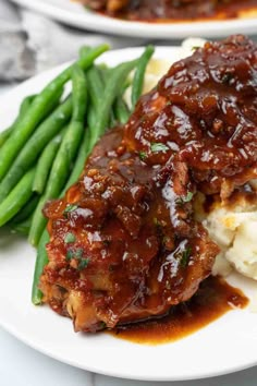 slow cooker honey garlic chicken thighs on a plate with mashed potatoes and green beans