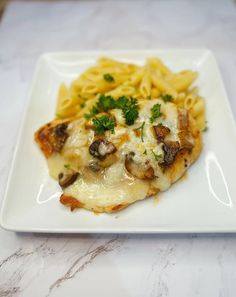 a white plate topped with pasta and meat covered in sauce