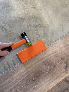 a person using an orange squirt to clean a wood floor