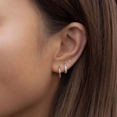 a woman wearing an earring with two small diamonds on the top of her ear