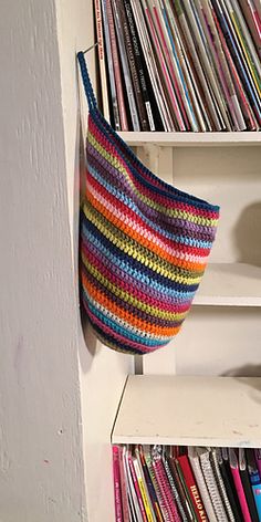 a crocheted bag hanging from the side of a white bookcase filled with books