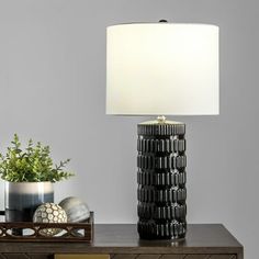 a table lamp sitting on top of a wooden dresser next to a potted plant