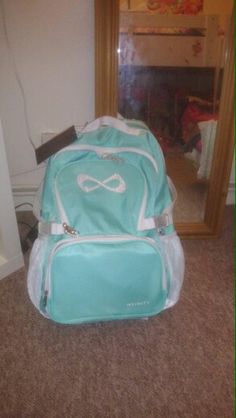 a blue and white backpack sitting on the floor in front of a mirror with a reflection