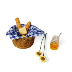 a basket filled with bread next to a jar of honey and a sunflower on a white background