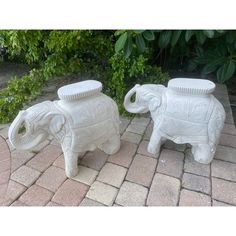 two white elephant statues sitting on top of a brick walkway