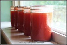 four jars filled with liquid sitting on top of a window sill