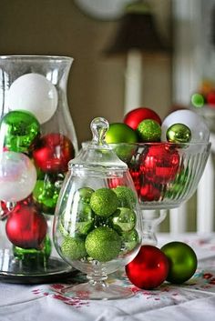 christmas decorations in glass vases sitting on a table next to other ornaments and decor