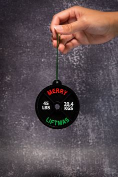 a hand holding a christmas ornament that says merry and has the time on it