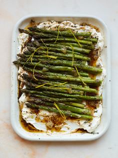 asparagus with goat cheese and seasoning in a white dish on a table