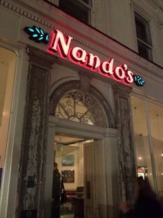 a neon sign on the side of a building that says nando's restaurant