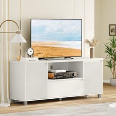 a flat screen tv sitting on top of a white entertainment center next to a lamp