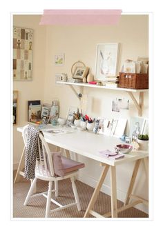 a white desk topped with lots of pictures and other items next to a wall mounted shelf