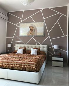 a large bed sitting under a painting next to a wall with geometric designs on it