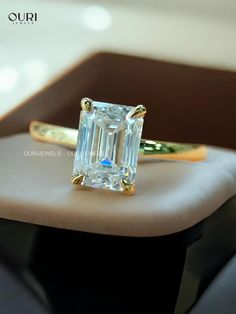 an emerald cut diamond sits on top of a gold ring