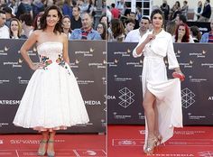 two women in white dresses standing next to each other on a red carpet with people watching