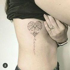 a woman with a tattoo on her stomach holding onto the side of her lower back