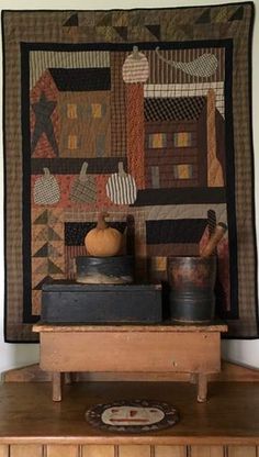 a table with a quilt on top of it next to a vase and other items