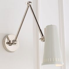 a wall light with a white shade hanging from it's side in a room