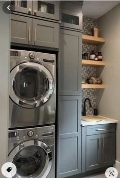 a washer and dryer are in the corner of this laundry room with built - in shelving