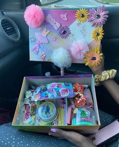 a person holding a box filled with items in the back seat of a car,