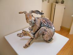 a sculpture of a rabbit sitting on top of a white table next to a refrigerator