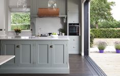 a kitchen with gray cabinets and white counter tops next to an open door leading outside