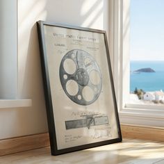 an old movie projector sitting in front of a window with the ocean behind it