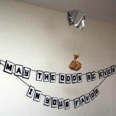 a party banner with the words may the odds be even in your bag hanging from a string