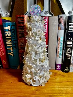 a christmas tree made out of seashells sits on a table next to books