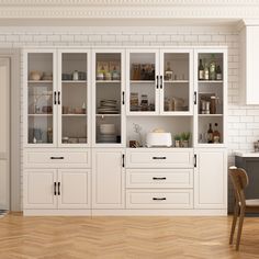 an empty kitchen with white cabinets and wood flooring, along with a dining room table