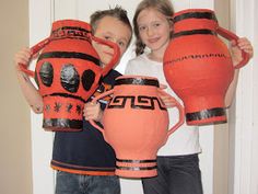 two young children holding up large orange vases