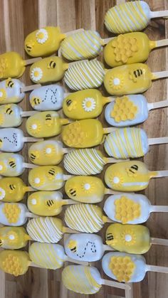 many yellow and white bees on sticks with honeycombs painted on them, sitting on a wooden surface