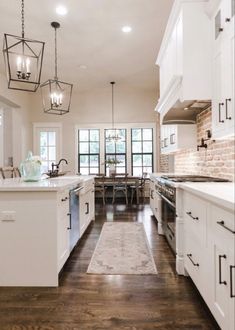 a large kitchen with white cabinets and wood flooring on the walls, along with an area rug that matches the hardwood floor