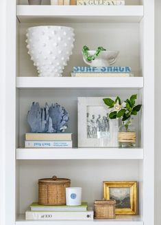 a white book shelf filled with books and vases