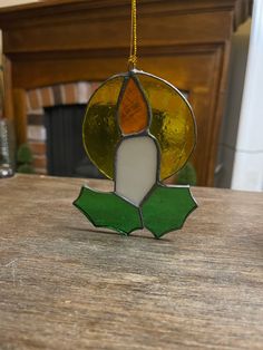 a stained glass ornament hanging on a table in front of a fire place