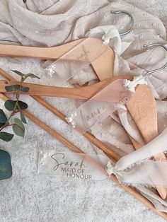 three wooden clothes hangers on top of a white cloth covered bed spread with flowers