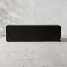 a black table cover sitting on top of a white tile floor next to a wall